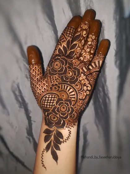 A fresh application of a floral henna design, featuring a mix of bold flowers and checkerboard filler patterns.