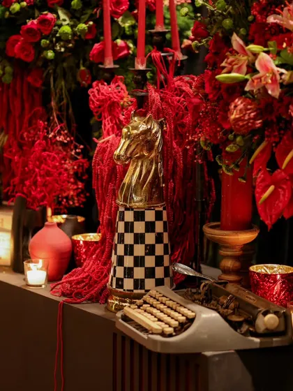 A curated corner of aesthetic details, combining classical art, vintage props, and bold checkerboard patterns with lush red floral arrangements.