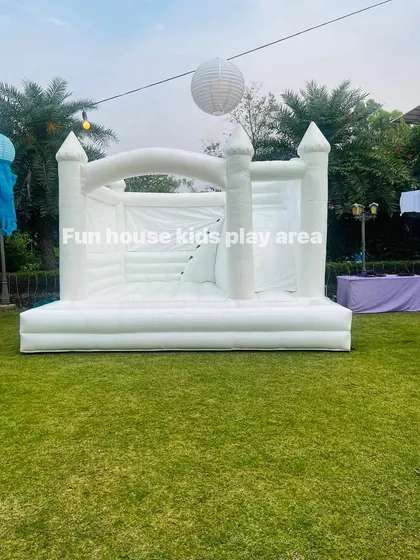 Our 15x15 foot All-White Dream Castle set up in a garden, ready for a day of fun. This four-in-one unit includes jumping, climbing, a slide, and a ball pit area.