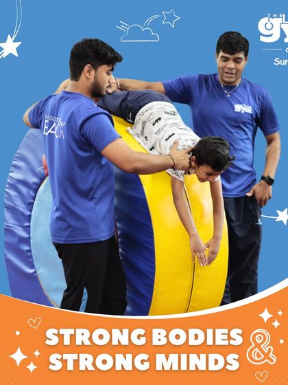 Our coaches are dedicated to helping every child succeed. Here, two instructors support a student on the barrel mat, ensuring safety while he learns a new skill.