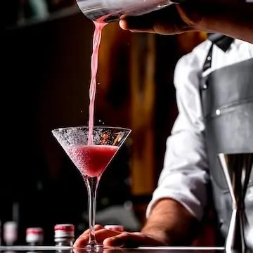 I love the craft of a good cocktail. This is a vibrant strawberry cocktail being poured from a shaker into a classic martini glass, showing the care and flair that goes into every drink.