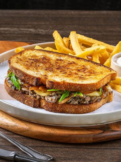 A mushroom and cheese grilled sandwich, with a focus on the melted cheese and toasted bread.