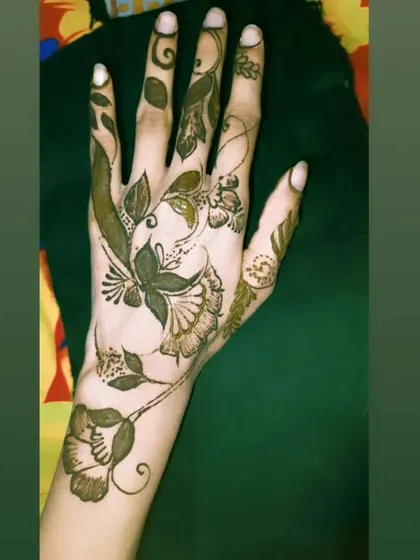 This is an example of a very minimalist and modern vine design. The delicate, leafy trail flows organically across the back of the hand for a subtle and elegant touch.