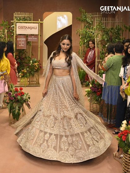 A model walks the runway at our Ahmedabad launch, showcasing a stunning lehenga and our glamorous hairstyling.