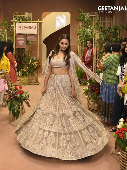 A model walks the runway at our Ahmedabad flagship launch. Her stunning lehenga is paired with soft waves and glowing makeup, a signature look from our talented team.