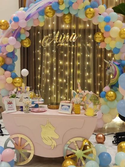 A whimsical unicorn-themed dessert cart filled with magical treats. This setup, complete with a pastel balloon arch and fairy lights, was the centerpiece for darling Ayra Yash's birthday celebration.