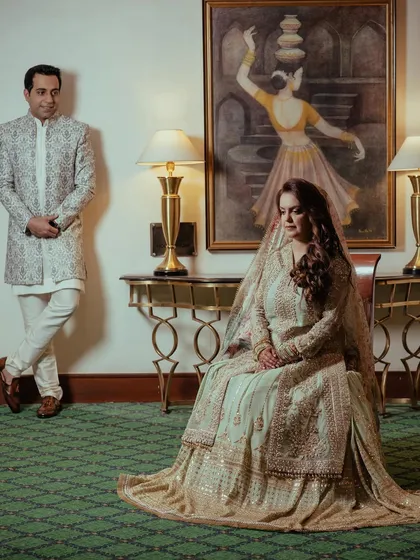 A regal portrait of the couple at their reception, posing in a hotel room with classic art and elegant furniture, creating a timeless and sophisticated feel.