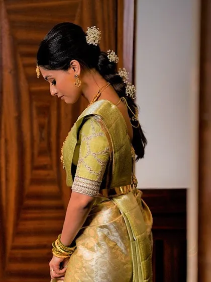 A client in a light green Kanchipuram saree. Her custom blouse features a simple, elegant design with subtle embroidery on the sleeves.