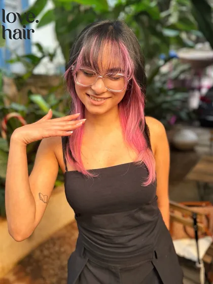 A happy client showing off her pink face-framing highlights. It's a fun and trendy look that's sure to turn heads.