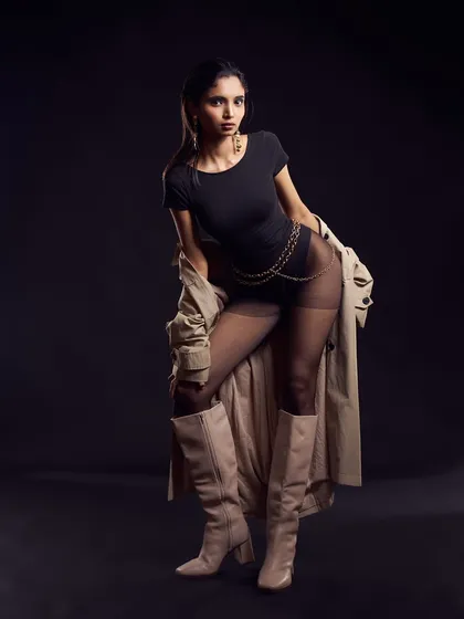 A powerful, direct-to-camera pose. The simple black bodysuit and trench are the perfect canvas for the bold lip and clean, pulled-back hair.