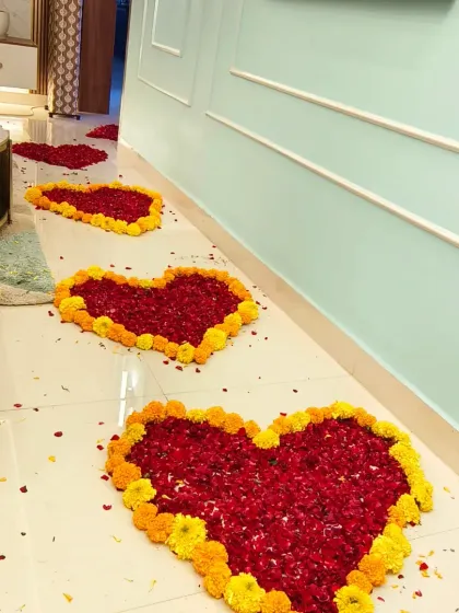 A beautiful pathway of heart-shaped flower arrangements made from red rose petals and marigolds, creating a royal welcome for a new baby girl.