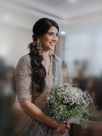 A candid shot of the smiling bride holding a bouquet of white flowers during her ring ceremony, capturing her natural joy.