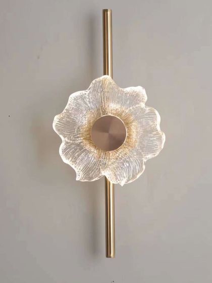 A flower-shaped wall light with a textured glass design on a brass stem. This piece adds a delicate and artistic touch to any wall.