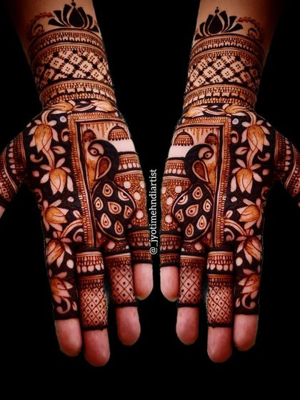 This is a classic example of heavy Indian bridal mehndi. The design features two prominent peacocks on the palms, framed by intricate floral work and geometric patterns for a full, rich look.