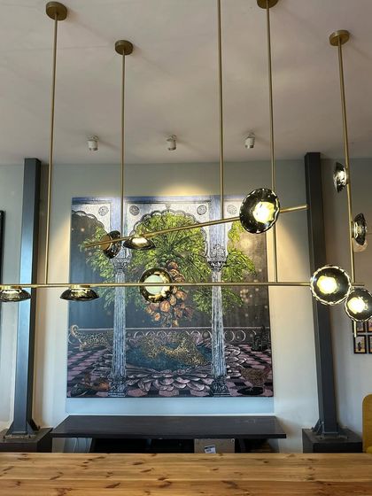 The Ceto chandelier on display in our gallery, its sculptural form set against a beautiful painting, creating a dialogue between light and art.