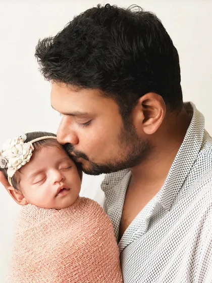 A father gently kisses his sleeping newborn's forehead. It's a simple, powerful gesture of love and protection.