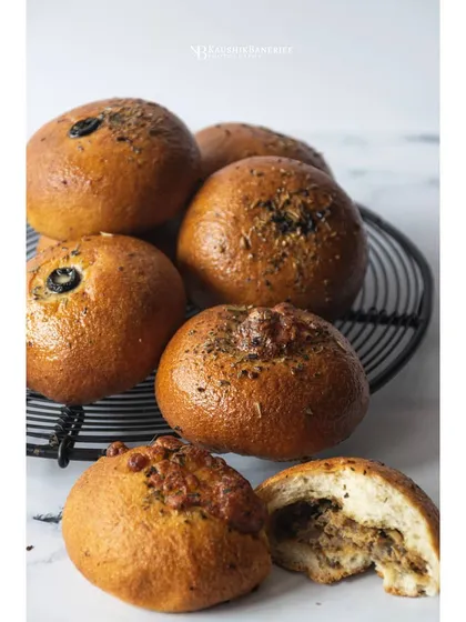 Freshly baked savory buns on a cooling rack. The bright, minimalist style and shallow depth of field draw attention to the glossy tops and soft texture of the bread.