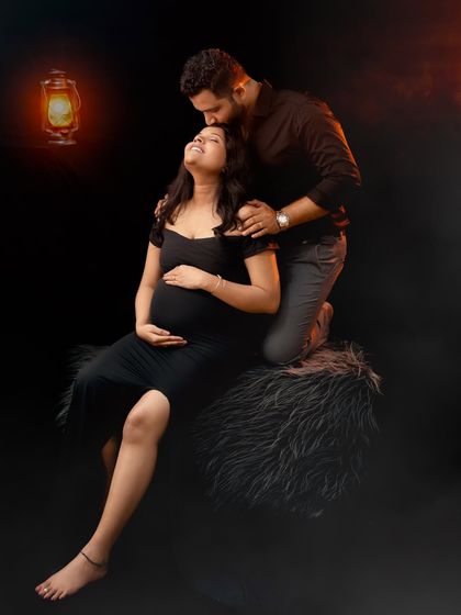 A dramatic and romantic couple portrait. Lit by the warm glow of a lantern, the partner kisses the mom-to-be's forehead in this intimate and moody shot.