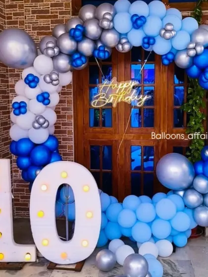 A 10th birthday celebration with a cool blue and silver theme. The setup includes a circular balloon arch and large light-up marquee numbers.