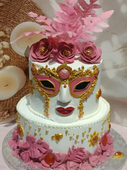 A dramatic two-tiered masquerade ball cake. This design features an ornate, handcrafted mask and vibrant pink sugar flowers.