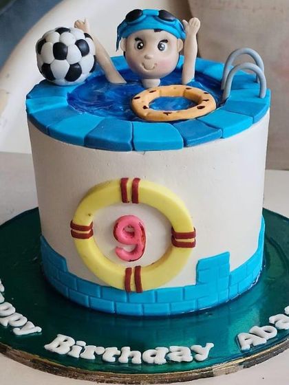 A fun-in-the-sun pool party cake, complete with a swimmer figure, a lifebuoy, and a soccer ball for a 9th birthday splash.