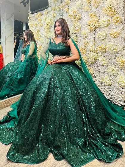 A client looking stunning in a fully-sequined emerald green ball gown with a long train. This is a show-stopping piece for any grand event.