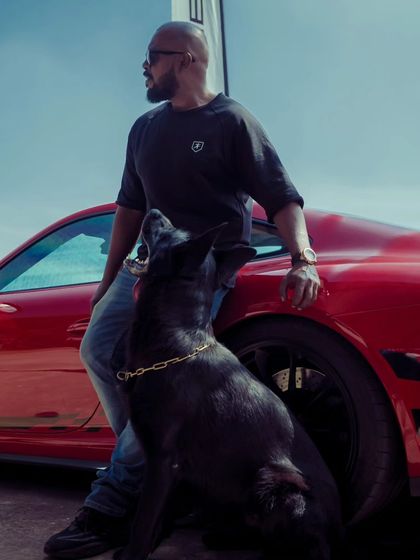 My dog looking up at me with complete focus, even with a stunning red Porsche right next to us. Our bond is stronger than any distraction.