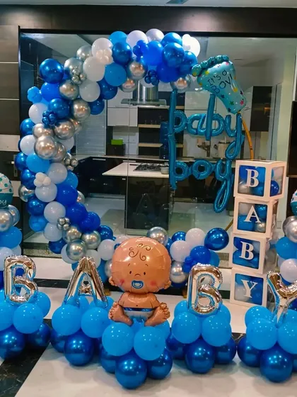 A grand "It's a Boy" welcome home decoration. The setup includes a blue and silver balloon arch, balloon pillars, "BABY" blocks, and the word "BABY" spelled out with foil balloons.