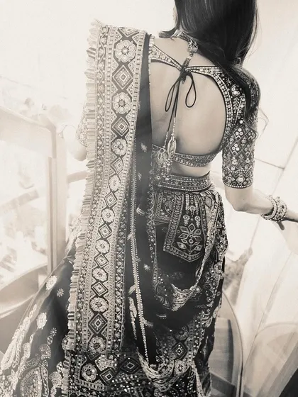 A black and white shot focusing on the stunning back and intricate details of this multi-colored lehenga, highlighting the craftsmanship of the blouse and skirt.