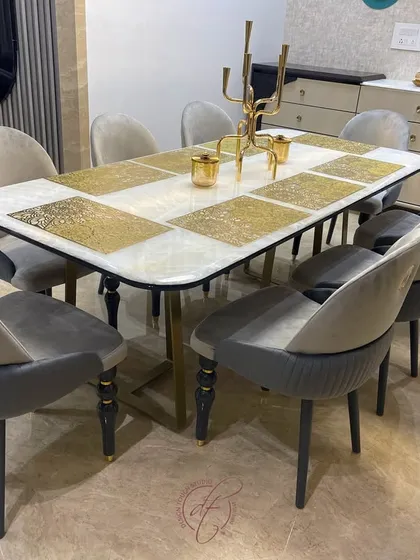 A close-up of the elegant dining table and chairs. The two-tone velvet upholstery on the chairs and the unique design of the table legs showcase our attention to custom furniture details.