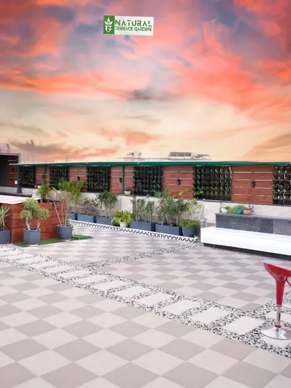 A wide terrace view showing a simple outdoor kitchen and bar setup with red stools, perfect for casual entertaining.