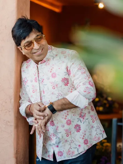 The father of the bride looking dapper in a floral print Nehru jacket paired with jeans. This is a great example of a smart-casual look for a pre-wedding event like a Haldi or Mehendi.