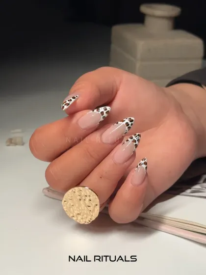 A side view of our popular cow print French tips. This angle shows the elegant shape of the nail extensions and the precision of the hand-painted design.