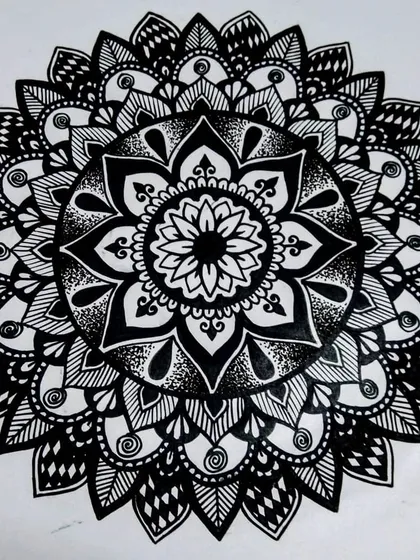 A finished floral-style mandala, drawn completely in black ink. This design is built around a central flower, with layers of petals expanding outwards. It's a classic style that's very satisfying to create.