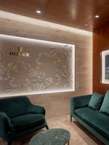 We designed intimate lounge spaces within the Rolex boutique for private consultations. This seating area features plush velvet armchairs in the brand's signature green and a back-lit wall with an abstracted Rolex motif, reinforcing the brand's heritage in a subtle, artistic manner.