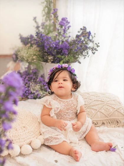 A lovely portrait of the one-year-old, framed by fresh purple flowers. The soft, natural light from the window adds a dreamy quality.