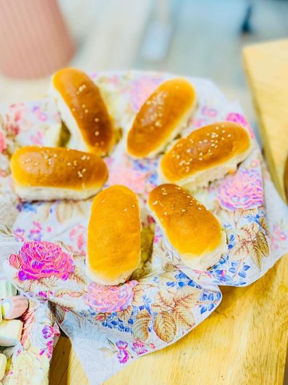 Delicious treats are a must at any tea party. A basket lined with a floral cloth holds freshly baked buns, part of the delightful spread we provide for the children.