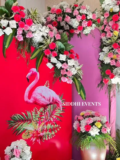 A close-up of the flamingo-themed Haldi decor, showcasing the vibrant colors and the beautiful arch of pink, red, and white flowers.
