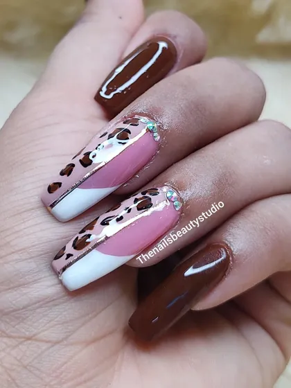 This bold design combines a classic white French tip with hand-painted leopard print and a solid chocolate brown polish for a trendy look.