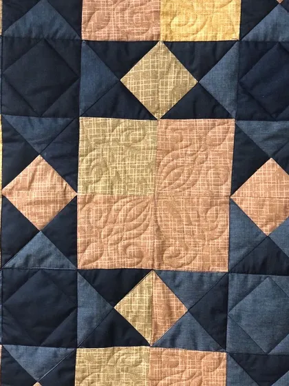 A close-up of a single block from the Sawtooth Star quilt, showing the custom quilting.