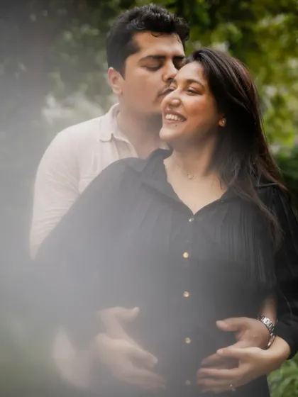 An intimate embrace, with the parents-to-be cradling the baby bump. The soft, dreamy foreground adds a touch of artistry to this special memory.