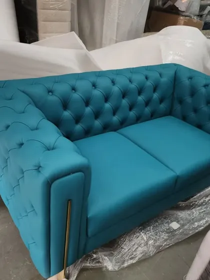 A custom-made chesterfield sofa in a vibrant teal fabric, ready for delivery. This piece features the classic deep button-tufting on the back and arms, with modern metal leg details.