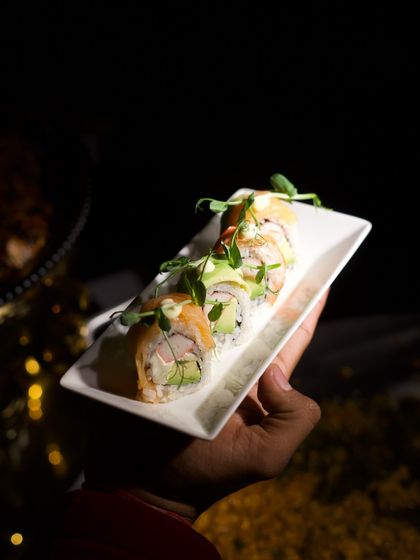 A server presents a plate of delicate salmon and avocado sushi rolls. We take pride in offering a wide range of international dishes, all prepared with authentic techniques and the freshest ingredients.