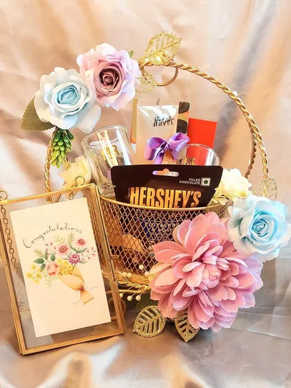 A congratulations hamper perfect for any achievement. This golden wire basket is filled with chocolates, treats, and a beautiful photo frame to hold a special memory.