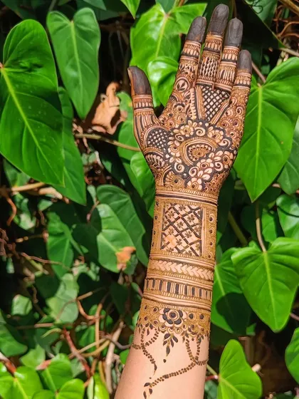 A single-arm design showing a mix of techniques, including geometric wristbands, fine-line netting, and bold floral work on the back of the hand.
