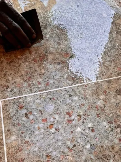 An artisan applies a finish to the terrazzo flooring at Kizikula. This handcrafted process, using local aggregates, creates a durable and beautiful surface that is unique to the project.