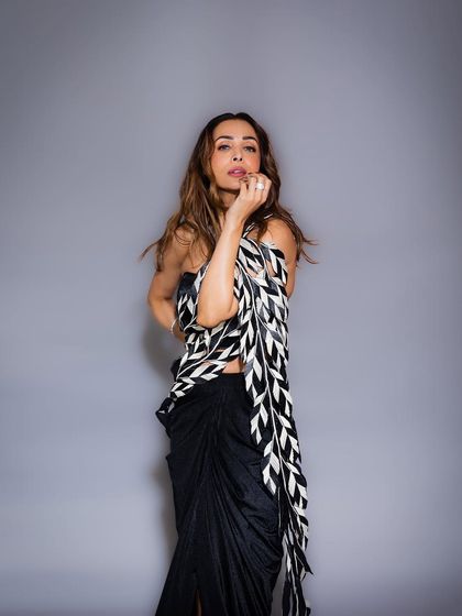 Full-length view of the modern saree look for Malaika Arora. The hair is styled with a middle part and loose, flowing waves to create a sophisticated and contemporary silhouette.