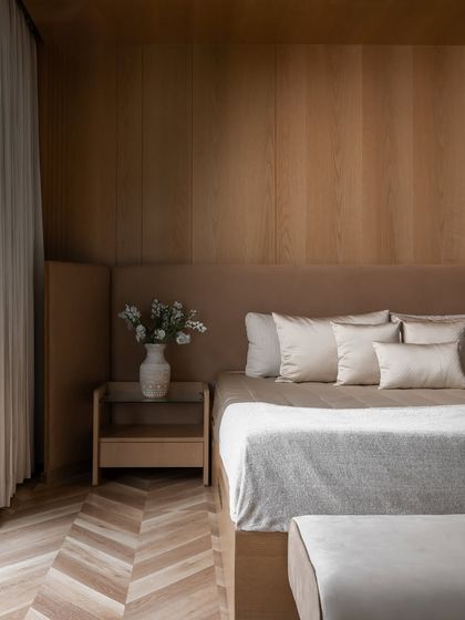 A detail of the master bedroom, showing the seamless integration of the upholstered headboard with the wood-paneled wall and the custom floating nightstand.