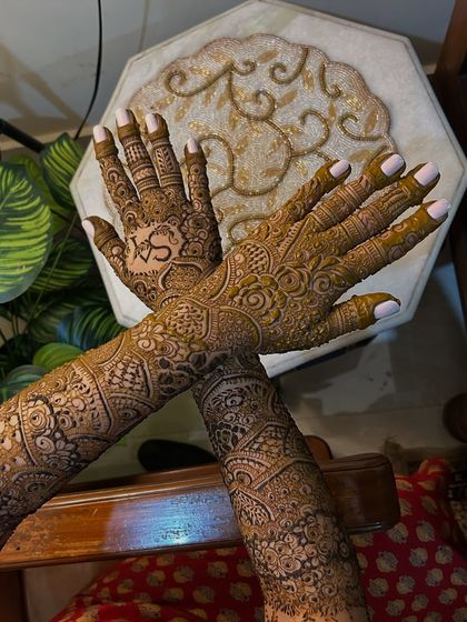 The crossed-hands pose shows how the intricate patterns flow seamlessly from the palms to the arms. This full-coverage look is a favorite among my brides.