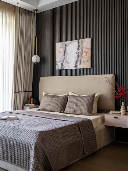 A sophisticated blend of textures and tones defines this bedroom. A dark, reeded timber backdrop is paired with light-hued furniture, creating an ethereal and inviting space. The look is completed with honey oak flooring and a neutral chenille fabric bed.